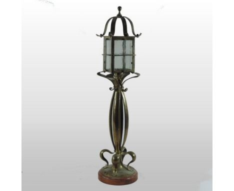 An Arts and Crafts style brass table lamp, in the form of a lantern, with a stylised column on a turned wood base, 64cm tall
