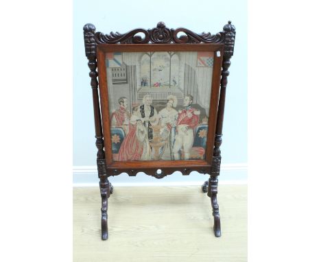 A Victorian carved mahogany fire screen, bearing a gros and petit point needlework depicting a royal Christening scene, a lab