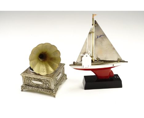 Two novelty petrol table lighters, comprising a tinplate model yacht on a plastic base, and a musical lighter formed as a gra