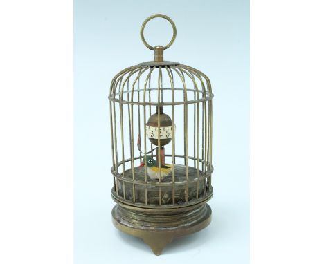 A 1950s brass bird cage automaton clock, having a keyless wind mechanical moment, an Arabic orbital dial, and a ticking bird,