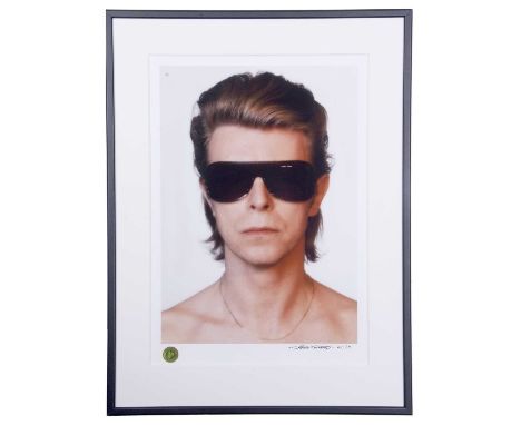 DAVID BOWIE Head and shoulders portrait of the artist in sunglasses. Measures 21 by 14.5”. Denis O’Regan is an English photog