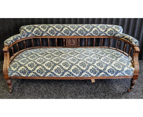 A Edwardian parlour settee, covered in a blue upholstery raised on carved turned legs