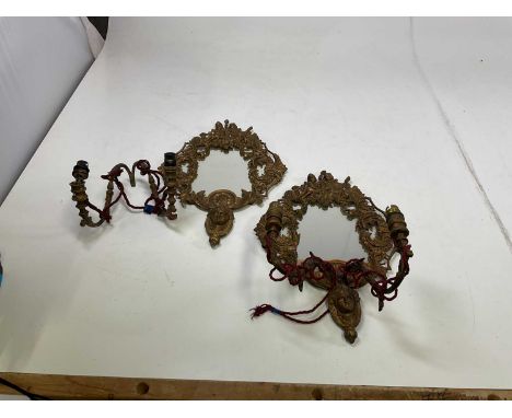 A pair of brass wall mirror lights depicting cherubs playing tennis, height 52cm, width 35cm.