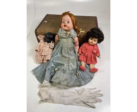 Three various vintage dolls in a vintage suitcase.