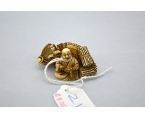 A JAPANESE IVORY NETSUKE man sitting beside a Water Buffalo signed to base