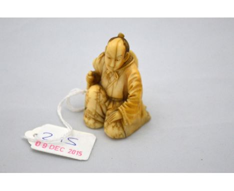 A JAPANESE IVORY NETSUKE, figure of a man kneeling with an axe, signed to base