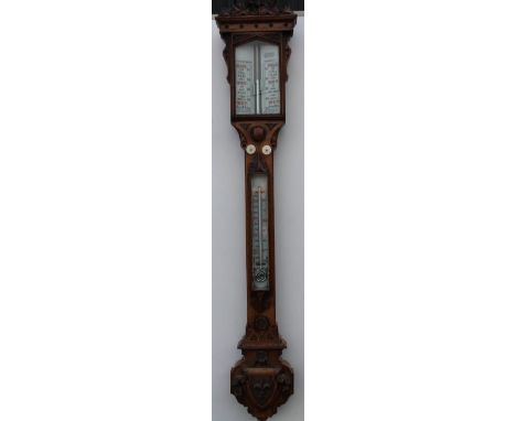 A Victorian oak stick barometer, the Gothic style case carved with shields, leaves, ivy, etc, with opaline glass register and