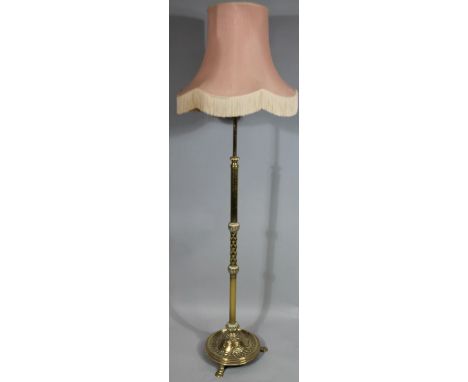 An early 20thC brass adjustable standard lamp, decorated with scrolls, lozenges, etc, on shaped feet, 193cm high, including s
