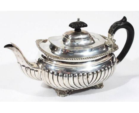 An Edwardian silver teapot, of cape form, partially gadrooned with an upper shaped border broken by shells, with ebonised kno