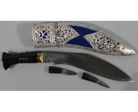 A 20thC Kukri knife, with elaborate shaped scabbard with silvered metal sections, with a polished handle and brass coloured p