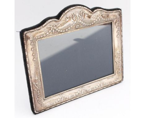 An Elizabeth II silver photograph frame, of Neo-Classical design, of shaped rectangular outline with serpentine top, the fram