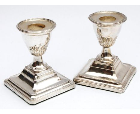 A pair of Edwardian silver dwarf candlesticks, each with acanthus based urn dish holders and stepped square bases, with cante