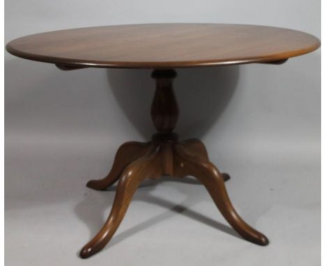 A modern Ercol dark wood dining table, the circular top raised on a baluster support, terminating in quadruple legs, 74cm hig