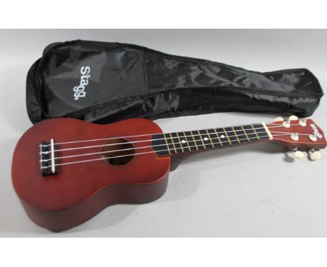 A modern Stagg handmade four string ukulele, with shaped body and articulated tuning knops, 52cm wide, in canvas case.