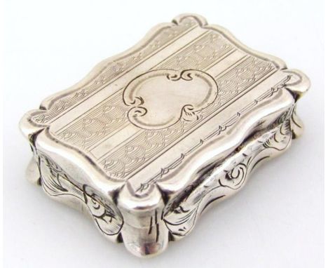 A Victorian silver gilt vinaigrette, of shaped outline with an engine turned lid, hinging to reveal an articulated meshwork s