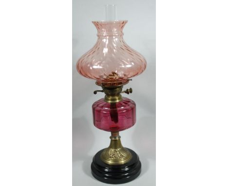 A Victorian cranberry glass and brass oil lamp, with clear glass funnel, cranberry glass reservoir, textured pink glass shade