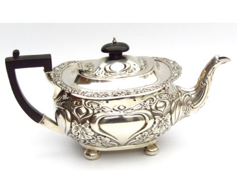 An Edwardian silver teapot, of cape outline with an upper flower head, scroll and orb border, the inverted compressed lid set