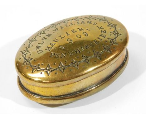 An Edwardian brass snuff box, of oval outline, the hinged lid reading GWLYN. WILLIAMS. HAULIER 1909 PENRHIWCEIBER. with an ou