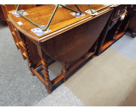 A mid-20thC oak oval gate-leg table raised on barley-twist supports