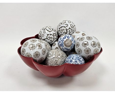 Quantity of printed ceramic spheres&nbsp;with scroll and stylised floral decoration in red lacquered bowl&nbsp;
