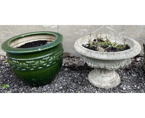 A reconstituted stone urn shaped planter with a swag of flowers together with a glazed stoneware planter