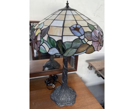 A Tiffany style table lamp, the domed glass shade with opaque panels and flower heads on a tree cast stem and spreading base