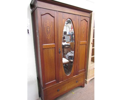 An Edwardian mahogany wardrobe, the moulded cornice above a central oval mirrored door, the base with a single drawer on brac