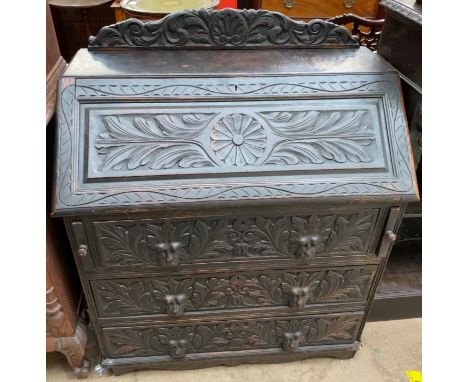 A 19th century Low Countries carved oak bureau, with a raised back, sloping fall, interior of pigeon holes and drawers above 