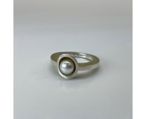 A two-toned modern silver ring elegantly encircling a lustrous pearl. Ring size is approximately 7. Marked 925. Dimensions: S