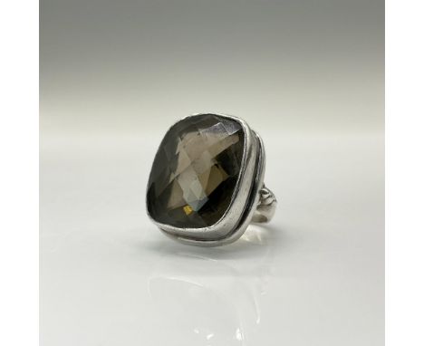 A sterling silver band and setting encircle a checkerboard-faceted smoky stone, creating a sleek and elegant design. The ring