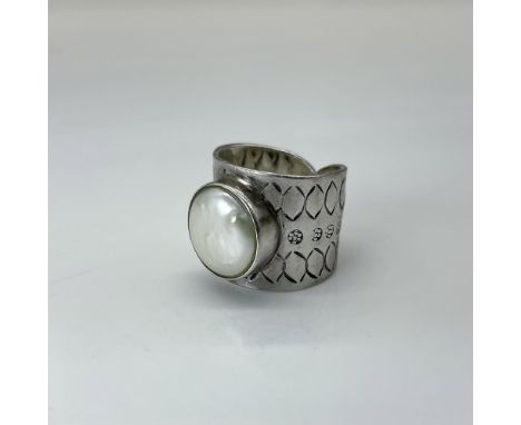 A stamped band featuring a rough, flat pearlized bead set in the mount, The ring is approximately size 6.75. Total weight is 