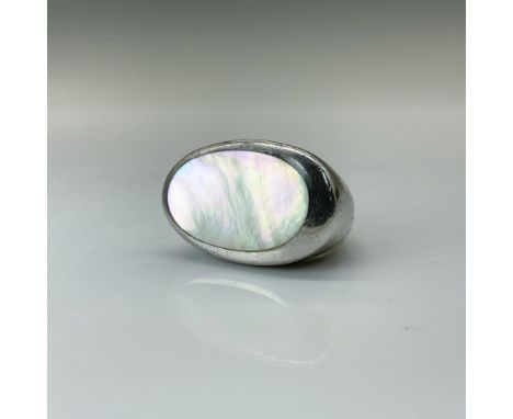 A lovely modernistic ring featuring a lustrous mother-of-pearl-like centerpiece, elegantly framed by sterling silver. Ring is