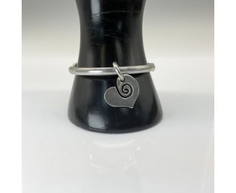 A circle ring bracelet with clasp opening decorated with heart pendant and cut out swirl. Marked 925. The bracelet is 2.5"Dia