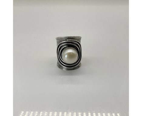Wide silver band with decorative groves and circle design featuring a large pearl in the center. Marked 925. This ring measur