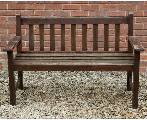 A brown stained teak garden two-seater bench with flat arms, 128cm wide x 59cm deep x 84cm highWeathered condition. Wear to t