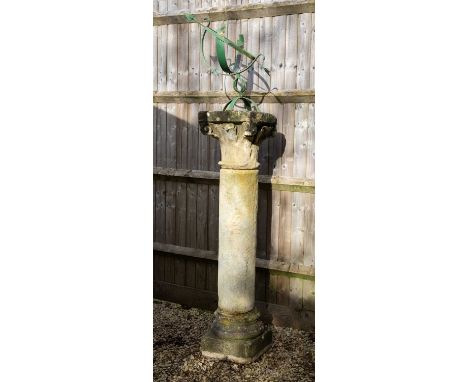 A sandstone column with decorative capital surmounted by a green painted wrought iron armillary sundial, the column 38cm squa