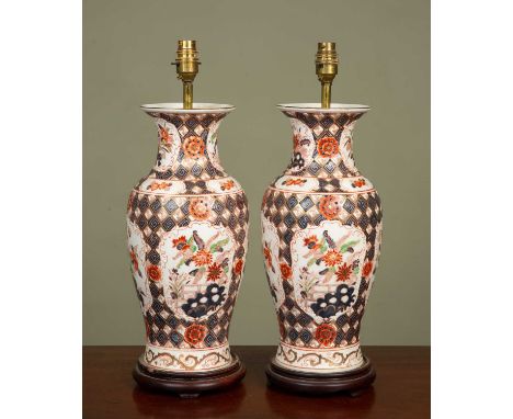 A pair of Japanese Imari style lamp bases, orange painted and decorated with flowers and butterflies, on wooden stands, 49cm 