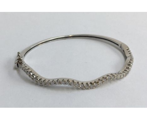 18ct white gold and diamond bracelet in the form of a hinged bangle. One side is set with approx. 1.20ct of small diamonds. G