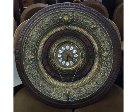 A brass clock, enamel dial with Roman numerals, set within a concentric brass and carved wood surround, with key, 71cmD 