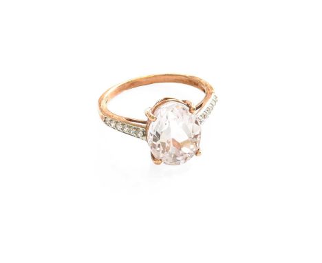 A 9 Carat Rose Gold Kunzite Ring, the oval cut kunzite in a four claw setting, to white zircon set shoulders, on a plain poli