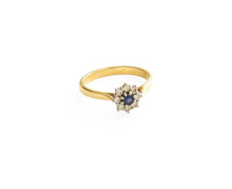 An 18 Carat Gold Sapphire and Diamond Cluster Ring, the round cut sapphire within a border of round brilliant cut diamonds, i