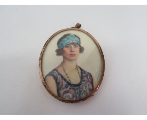 A hand painted portrait pendant of a 1920's lady wearing a blue dress and a feathered headband indistinctly signed lower righ