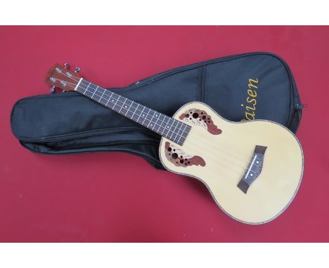 A Paisen guitar-form ukulele with pierced foliate sound holes, soft cased, with stand 