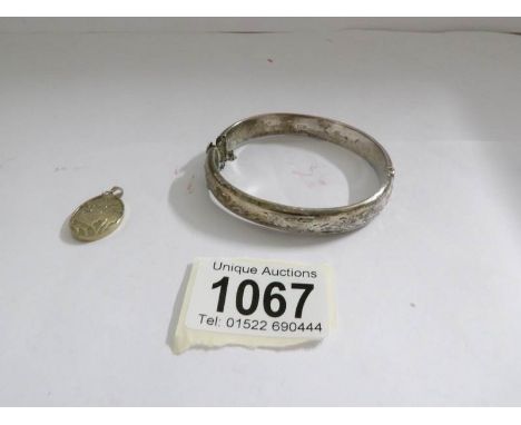 A silver bangle and  a jade pendant in a yellow metal 'relief' frame.