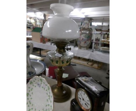 A brass oil lamp with glass font and shade.