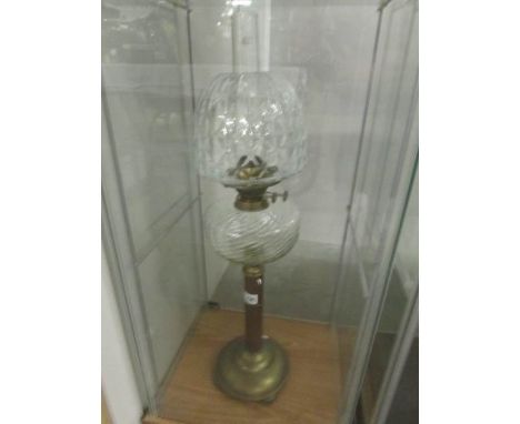 A brass oil lamp with clear glass font and shade.