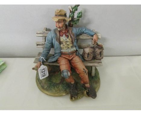 A Capo-di Monte figure of a tramp on a bench.