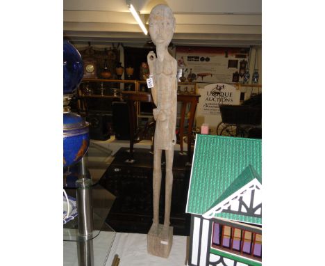 An early 20th century tribal art tall carved figure of a man holding an item (item missing), possibley Madagascan.