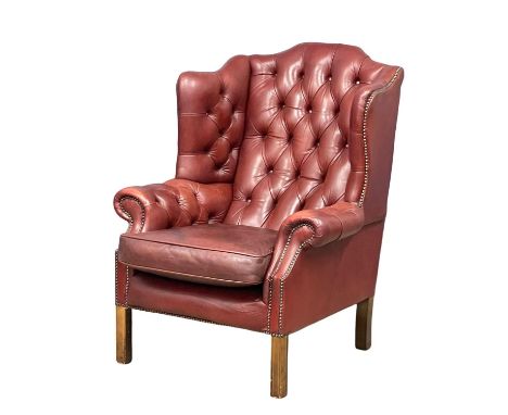 A large Georgian style deep button ox-blood leather wingback armchair. 