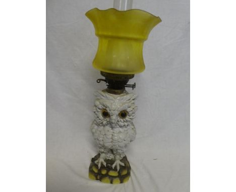 A Continental china oil lamp in the form of an owl with brass mounts and yellow tinted glass shade, 21" high overall